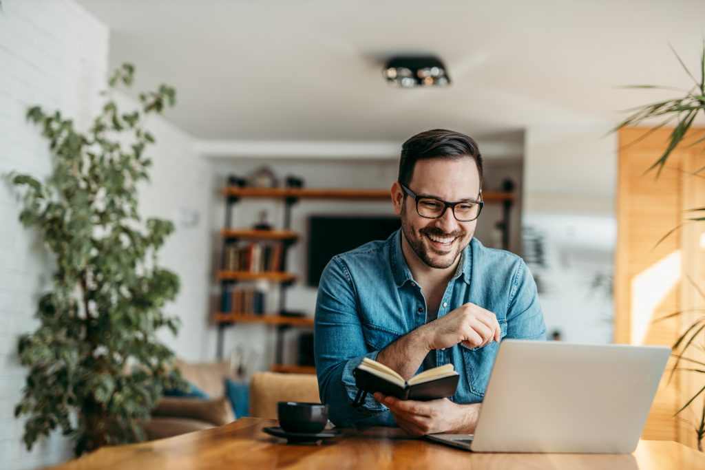 Smiling man sitting in front of his laptop at home