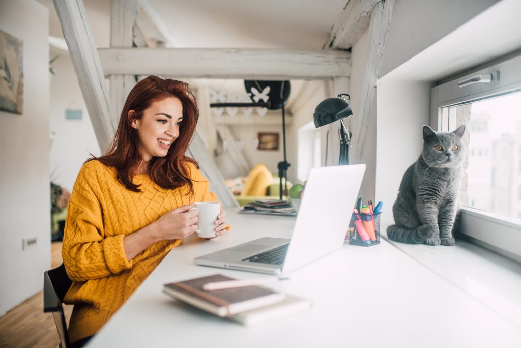 Smiling woman sitting in front of her laptop at home Smiling woman sitting in front of her laptop at home