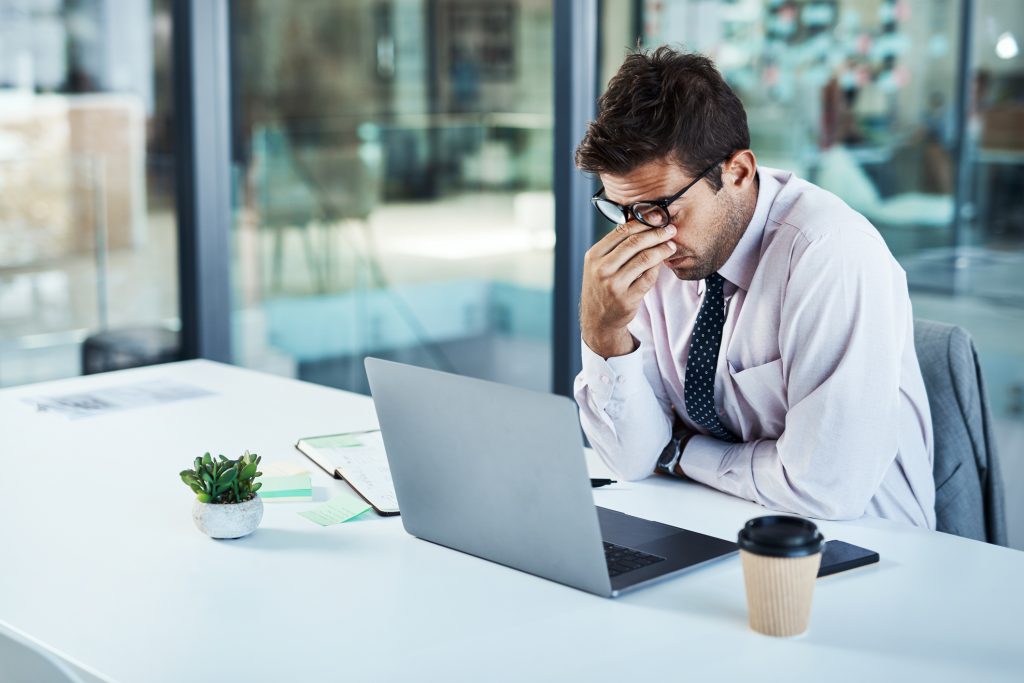 Tired employee sitting in front of his laptop in an office